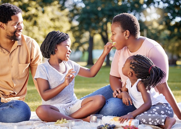 Letnie piknikowe i szczęśliwe z czarną rodziną w parku jedzące owoce razem dla opieki, więzi lub wakacji Wakacje szczęśliwa rodzina i zdrowie z rodzicami i dziećmi siedzącymi w środowisku wiejskim