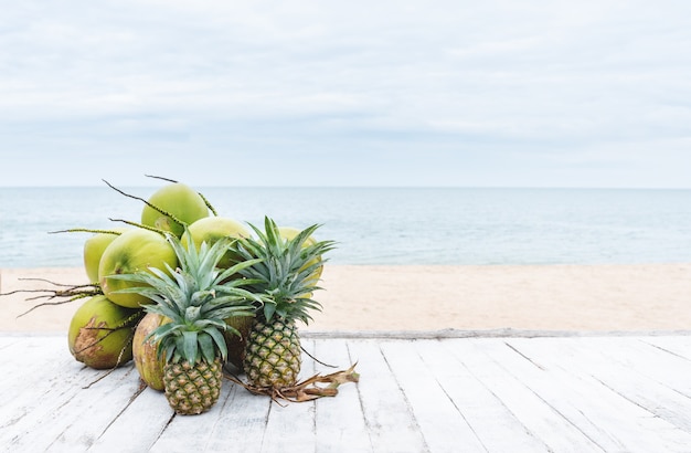 letnie tło kokosy i ananasy na białym drewnianym stole na plaży latem