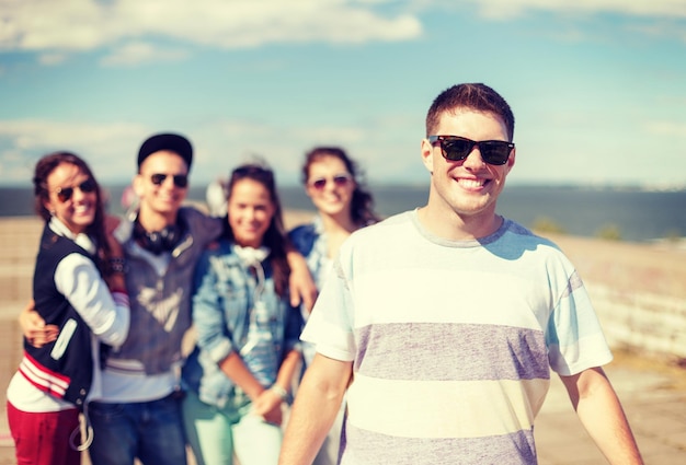 letnie wakacje i nastoletnia koncepcja - nastoletni chłopak w okularach przeciwsłonecznych spędzający czas z przyjaciółmi na zewnątrz