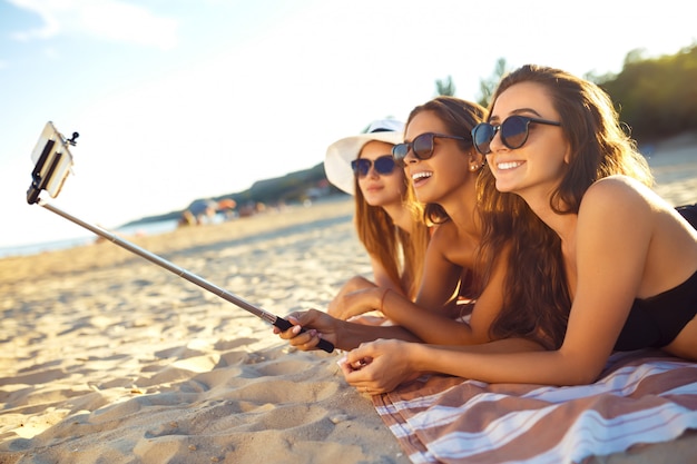 Letnie wakacje i wakacje - dziewczyny opalające się na plaży. Dziewczyny robią selfie telefon. ciesz się latem. Zabawa na plaży. Świetny letni nastrój. słoneczny dzień