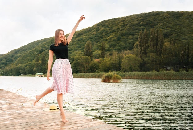 Letnie wakacje piękna młoda kobieta pozuje elegancko stojąc na molo nad morzem kopiuj spa