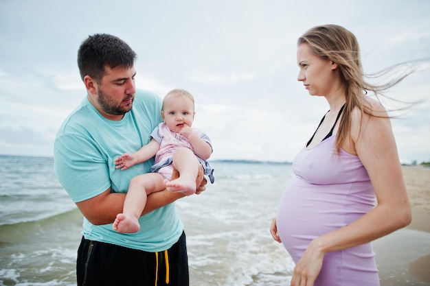 Letnie wakacje Rodzice i ludzie aktywność na świeżym powietrzu z dziećmi Szczęśliwe rodzinne wakacje Ojciec w ciąży matka córeczka na morskim piasku plaży