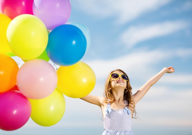 Zdjęcie letnie wakacje, uroczystość, rodzina, dzieci i ludzie koncepcja - szczęśliwa dziewczyna z kolorowymi balonami