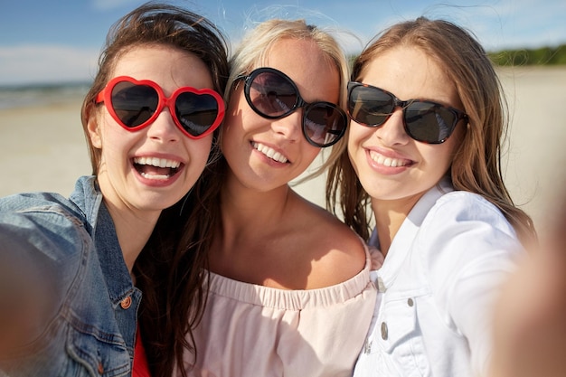 letnie wakacje, wakacje, podróże i koncepcja ludzi - grupa uśmiechniętych młodych kobiet robiących selfie na plaży