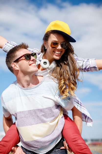 letnie wakacje, związki i nastoletnia koncepcja - uśmiechnięte nastolatki w okularach przeciwsłonecznych bawiące się na zewnątrz