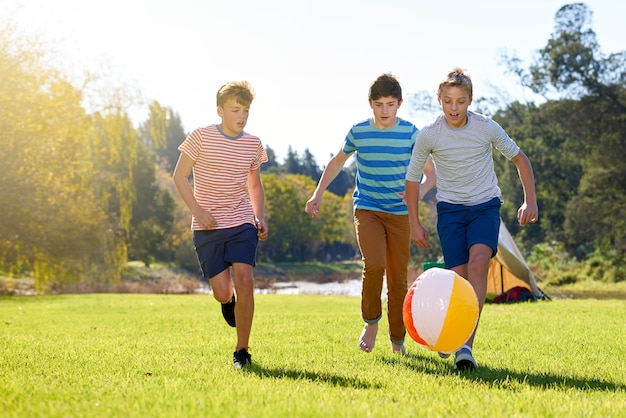 Letnie wspomnienia w ruchu Ujęcie grupy nastoletnich chłopców bawiących się piłką na świeżym powietrzu