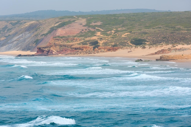 Letnie wybrzeże Atlantyku i piaszczysta plaża Praia da Bordeira. Mglisty widok (Carrapateira, Algarve, Portugalia).