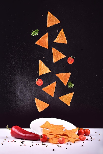 Zdjęcie lewitujące chipsy ziemniaczane na czarnym tle z sosem