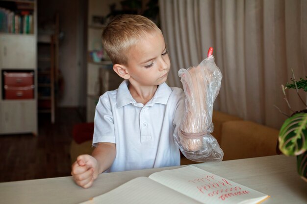 Leworęczny Chłopak Włożył Lewą Rękę W Plastikową Rękawiczkę, Aby Uniknąć Bałaganu Międzynarodowego Dnia Leworęcznych