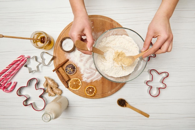Zdjęcie leżał płasko. ręce kobiety mieszanie suchych składników w misce mąki podczas przygotowywania ciasta piernikowego na świąteczne ciasteczka. jedzenie, kulinaria, celebrowanie świątecznych imprez tradycyjnych