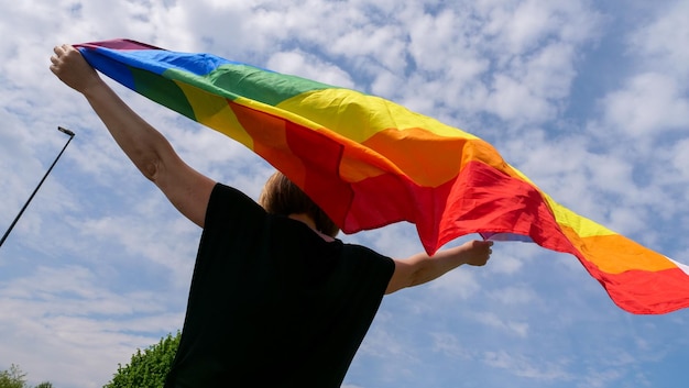 Lgbt duma tęczowa flaga pokoju na tle błękitnego nieba z chmurami w słoneczny dzień i świętuj biseksualność