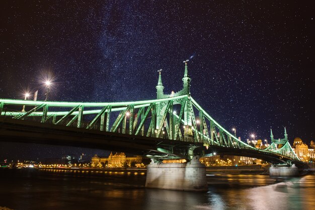 Liberty zielony most w nocy w Budapeszcie z oświetleniem i gwiaździstym niebem, tło miasta na zewnątrz podróży