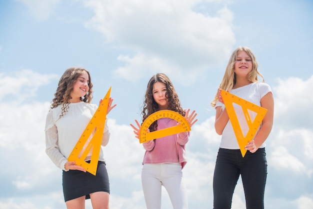 Liceum trzy dziewczyny z kątomierzem i trójkątną linijką powrót do szkoły STEM dyscypliny szkolne matematyka i koncepcja ludzi geometryczne kształty nowoczesna koncepcja edukacji siostrzane