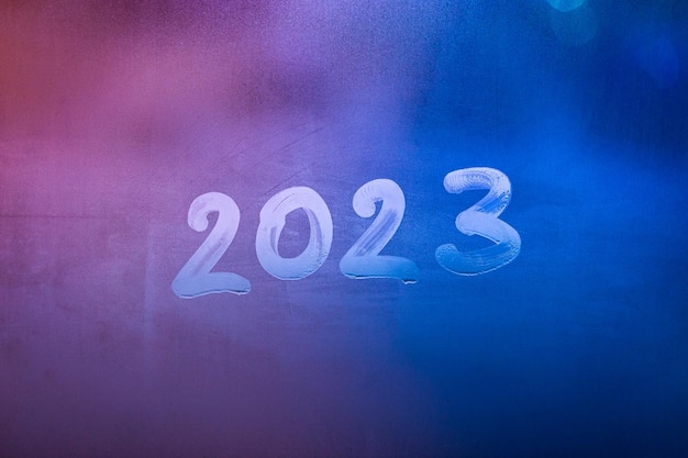 Liczba 2023 ręcznie napisana na mokrej powierzchni szkła okna nocnego, zbliżenie z selektywnym skupieniem