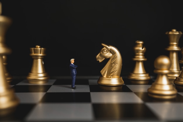 Zdjęcie lider biznesmen stoi z ufnością przed szachowymi końmi.