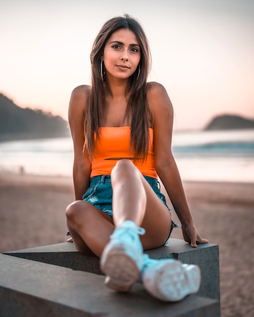 Lifestyle, młoda brunetka w pomarańczowym topie na plaży
