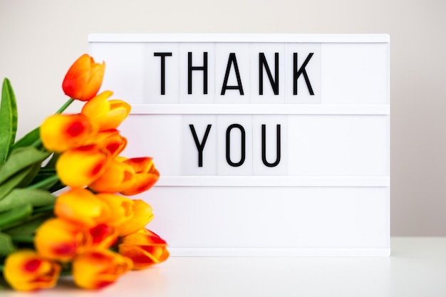 Zdjęcie lightbox z tekstem dziękuję i kwiatami tulipanów na stole