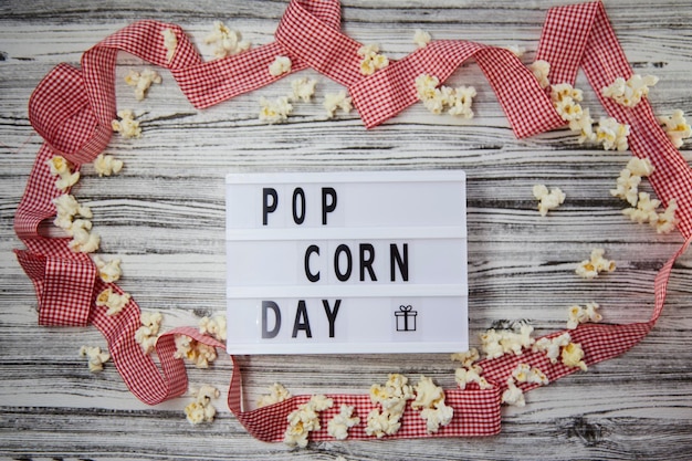 Lightbox z tekstem Dzień Popcornu wśród popcornów i tła świątecznej czerwonej wstążki Widok z góry Styl Vintage