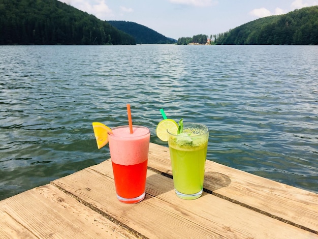 Zdjęcie limonada truskawkowa i limonada miętowa ze słomkami na drewnianym pontonie w pobliżu jeziora