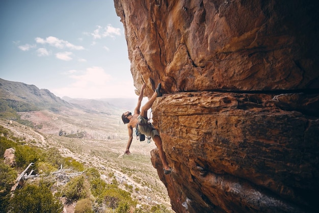 Lina wspinaczkowa i nieustraszony alpinista na klifie duże skały i ryzykowne wyzwanie samotnie latem Alpinizm bouldering i silny mężczyzna trenujący swoje ciało do równowagi na zewnątrz w przyrodzie