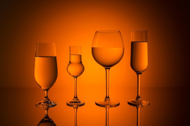 Linia różnych szklanek alkoholu na pomarańczowym tle zachodu słońca. Zrobione w Studio ze znakiem 5D III.