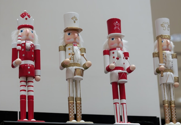 Zdjęcie linia żołnierzy łamaczy orzechów w czerwonym i białym mundurze drewniane figurki świąteczne na półce święty mikołaj na białym tle zestaw figur drewnianych łamaczy orzechów lalka na półce w sklepie z zabawkami