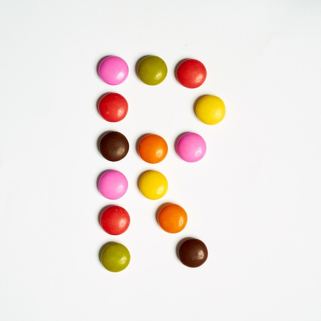Litera R słodkich kolorowych cukierków, alfabet na białym tle. R.