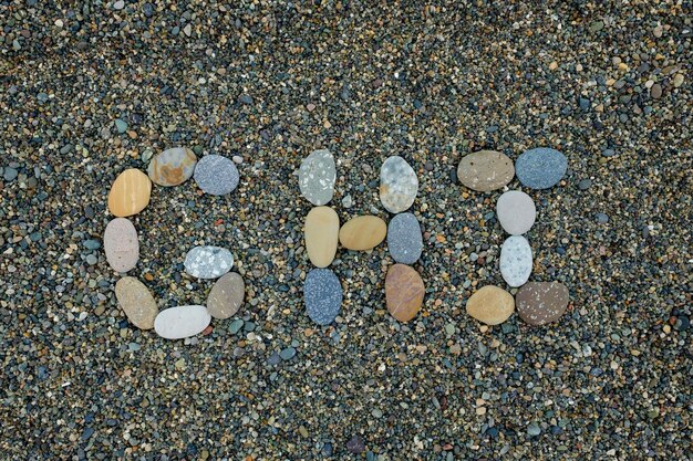Litery ghi wykonane z kamieni w piasku na plaży