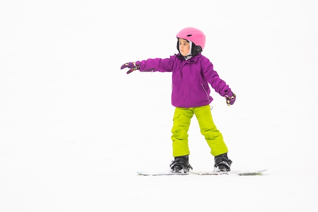 Little Cute Girl Snowboarding w ośrodku narciarskim w słoneczny zimowy dzień.