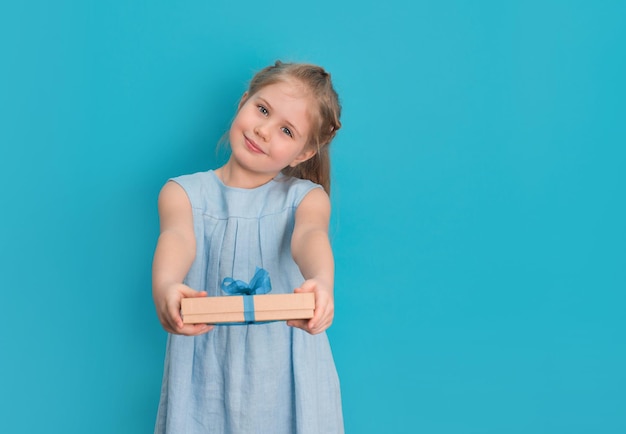 Little girl podając teraźniejszość na niebieskim tle Pudełko w rękach dzieci