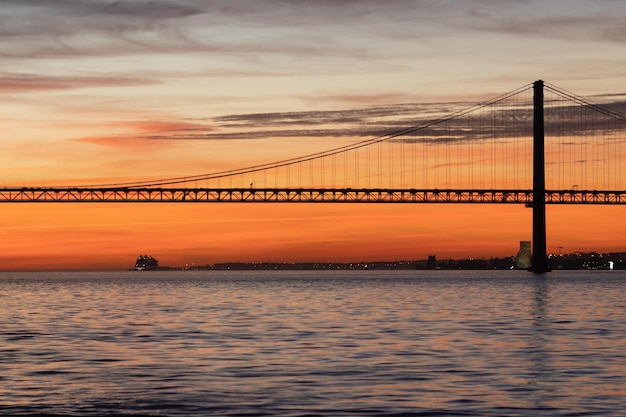 Lizbona i most kwietnia o pomarańczowym zachodzie słońca