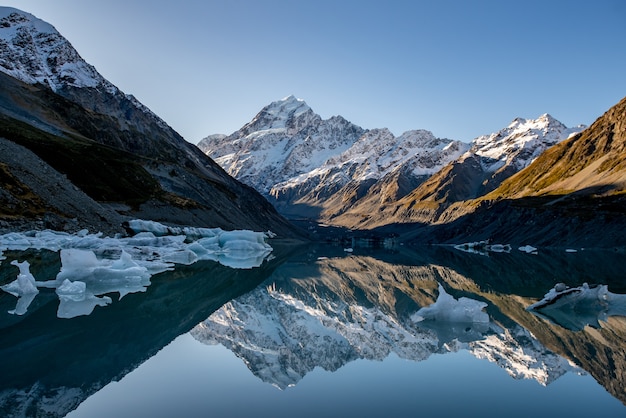 lodowe góry unoszące się na powierzchni odbijającej Mount Cook w Hooker Valley