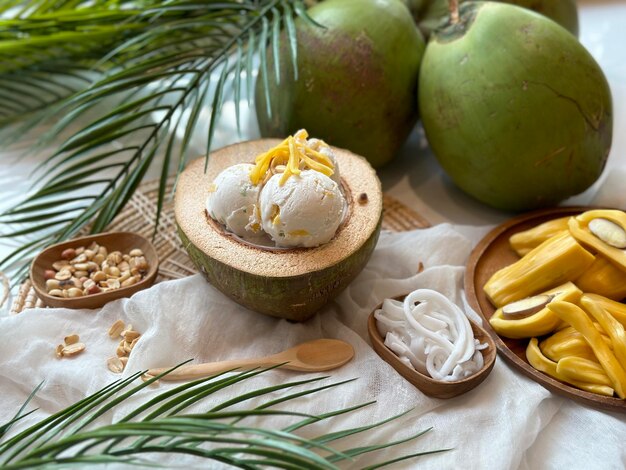 Lody kokosowe w drewnianej misce z kokosami i kokosami na białej szmatce.