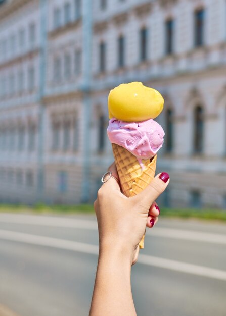 Lody Stożek W Ręku Zbliżenie Z Bokeh. Lody O Smaku Sorbetu Brzoskwiniowego I Lawendy. Zdjęcia Z Wakacji. Podróż Do Włoch. Piękny Manicure Z Lodami. Pomysł Na Deser Z Miejscem Na Kopię.