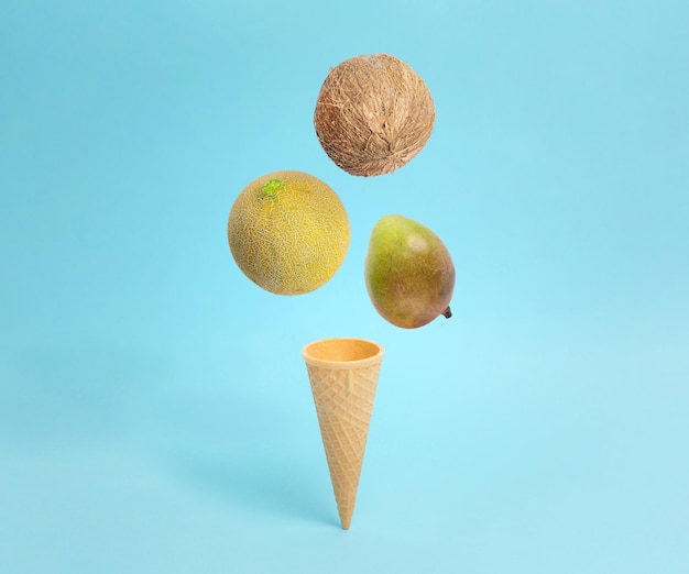 Lody w rożku z melonem kokosowym i mango Fall Kreatywna kompozycja koncepcyjna na pastelowym błękicie