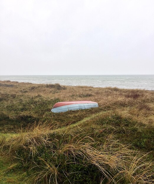 Zdjęcie Łódź do góry nogami na trawiastej plaży na czystym niebie