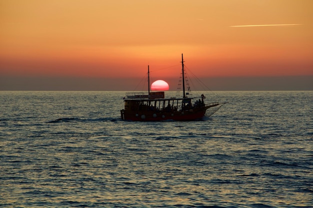 Zdjęcie Łódź pływająca na morzu na tle nieba podczas zachodu słońca