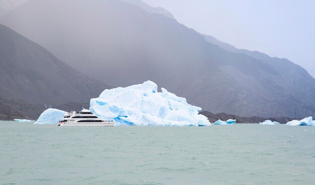 Łódź przepływająca przez górę lodową na wodach Patagonii
