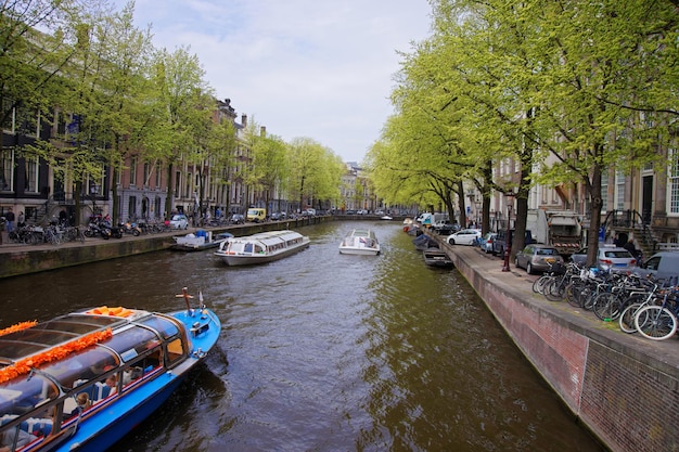 Łodzie Wodne Na Kanale Rzeki Amstel I Budynki Na Nabrzeżu Amsterdamu, Holandia.