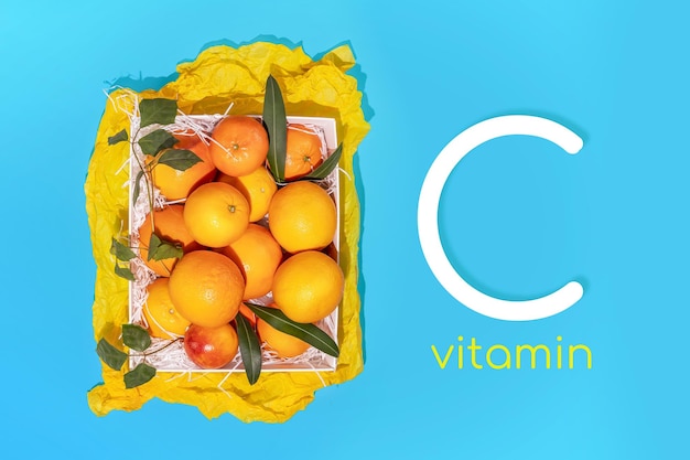 Lokalnie uprawiane organiczne owoce cytrusowe to naturalne witamina C Horizontalna letnia kompozycja słonecznych owoców z świeżymi pomarańczami w białym pudełku na niebieskim tle z inspiracją witaminy C