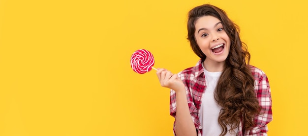 Lollipop dziecko hipster dziecko z długimi kręconymi włosami trzymać lollypop cukier cukierek na patyku Nastolatek dziecko ze słodyczami plakat baner nagłówek kopia przestrzeń