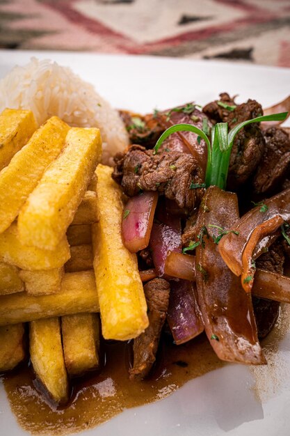 Zdjęcie lomo saltado z ryżem i frytkami i zieloną dekoracją