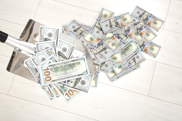 Łopata podnosi banknoty dolarowe na podłodze