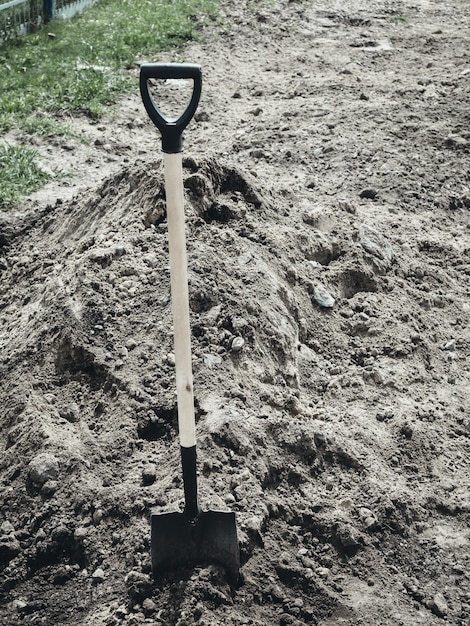 Zdjęcie Łopata utkwiła w kopie ziemi świeży grób lub pochówek na cmentarzu tło