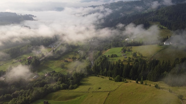 Lot nad małą wioską w górach w letni poranek we mgle