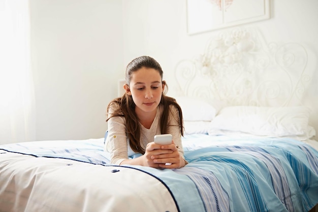 Łóżko nastolatka i dziewczyna z rozmową telefoniczną lub wysyłaniem SMS-ów w mediach społecznościowych cyfrowych i aplikacji na komórce Sypialnia dziecko i kobieta z technologią do relaksu łączyć się i komunikować się z internetem online