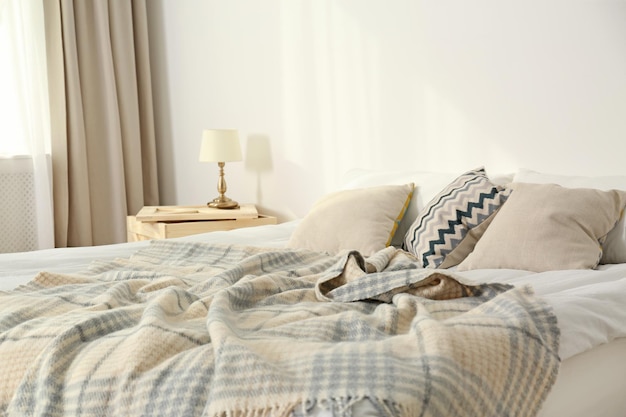 Łóżko z poduszkami i kratą w pobliżu jasnej ściany Przytulny wystrój wnętrz