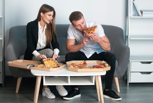 Ludzie biznesu ma pizzę na obiad para je pizzę w biurze