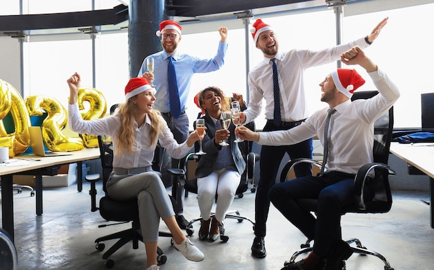 Ludzie biznesu świętują wakacje w nowoczesnym biurze, pijąc szampana i bawiąc się w coworkingu. Wesołych Świąt i Szczęśliwego Nowego Roku 2022.
