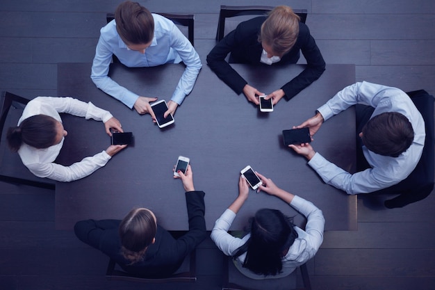 Ludzie biznesu ze smartfonami siedzącymi wokół widoku z góry stołu